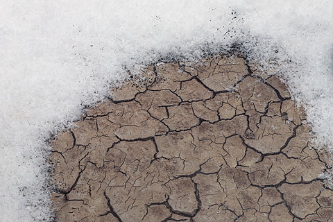 A close up of fake snow on a cracked dirt surface.