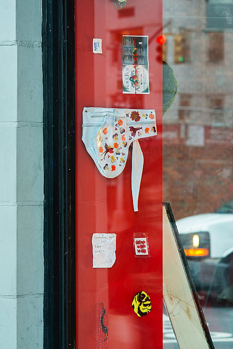 Various items, including a denim fabric scrap and a, hang against a red background.