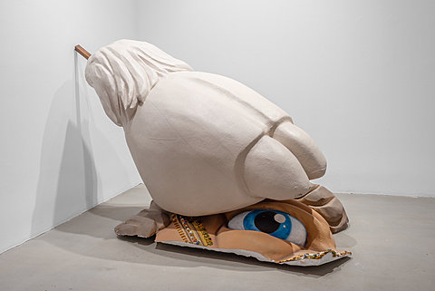 A large styrofoam camel's foot rests on a fragment of a painted camel statue's face.