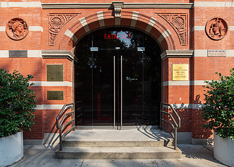 An exterior view of a red building. The text "FATAL ACT" glows in red light through an arched glass doorway.