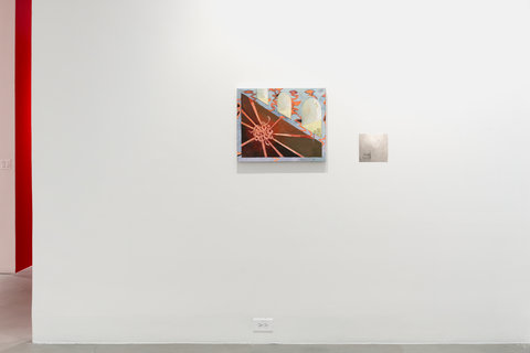 Installation view of two works in the exhibition, hung on a white wall. The first work, on the left, features abstract forms, cut across diagonally on the canvas. On the bottom left half of the diagonal, is what seems to be a ball of orange yarn and rope, with tethers coming out in all directions. Above the diagonal, on the right, are three arc shaped windows, but because of the angle, one cannot see out of them. The windows are green and blue and the blue walls between the window cut outs are littered with orange squiggly lines. On the right, is faint sketch on a light grey square paper much smaller than the first painting. 