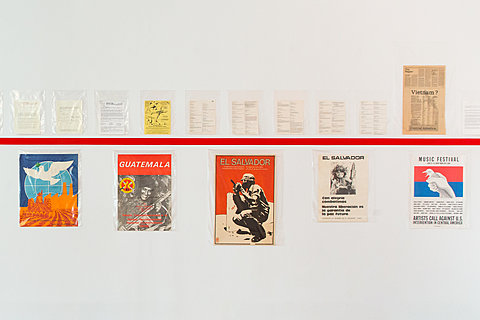Various posters and typed pages of text are displayed above and below a painted red line.
