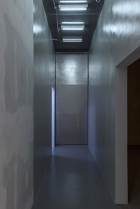 A hallway with shiny walls and soft blue flourescent lighting.