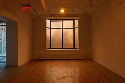A window is covered with translucent film in a room lit by a warm sodium light.