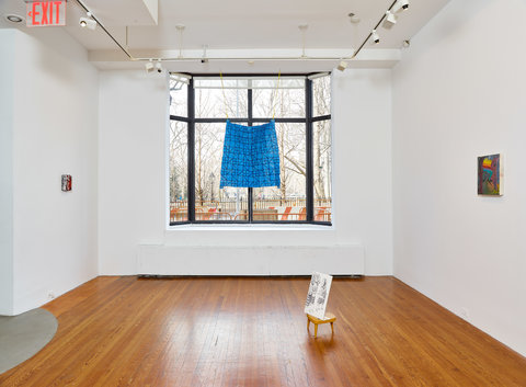 Installation view of the exhibition of two walls on either side of a large, three panel window. On the left wall is a very small painting, besides the red and white colors, it is illegible from the camera's point of view. In the center, a large blue square hangs over the window. On the square are black squares and line designs. On the right wall, there is a painting that features a rainbow Apple computers logo. In the front of these works, in the center on the floor, is a small sculpture that features a black and white outline of figures on a small wooden stool. 