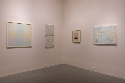 Installation view of two walls that meet in the corner. The walls are light pink. The left wall and the right wall both have two pieces hanging next to one another. The painting on the left wall consists of six overlapping squares in different muted, pastels of blue, green orange, yellow, and purple. The painting on the right features two black and white sketches, one hung above the other. The sketches consist of mandala-like drawings. On the right wall, there is a painting of items on a table, and next to this painting is a painting of a person peering through a rectangular window. 