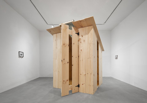 Gallery installation view of a large wooden structure. 
