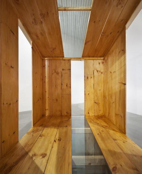 Inside view of a large wooden structure in which there are cut-out windows on either side. 