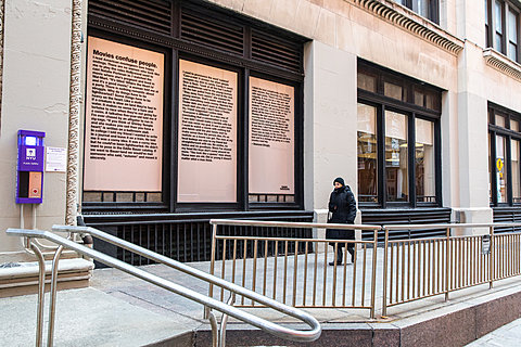 An oblique shot of the facade of a building with a window covered with a long poem.