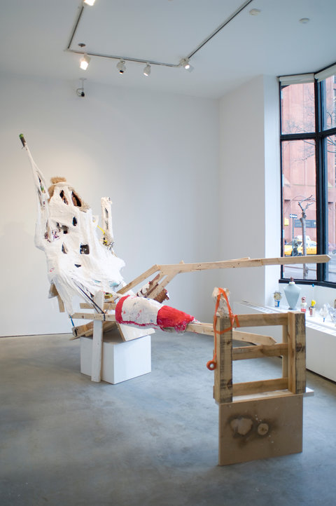 Installation view featuring two sculptures in the exhibition. Windows on the right side of the image, pour light into the room. The structure is made of wood, and white paper mache. 