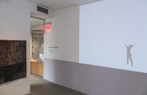 Installation view of the exhibition featuring several works in the exhibition. On the left, a painting is hung against a white wall featuring dark colors. In the middle, a sculpture hangs from the ceiling. 