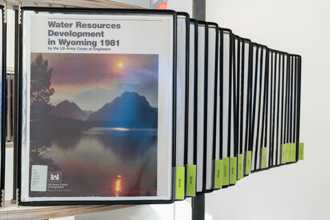 Close-up image of the installation featuring several images and articles from the archive bound in plastic in a row. 