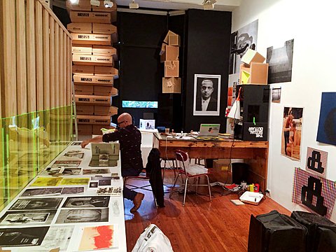 The image is of an office where a man is sorting through printed images laid out on a table.  