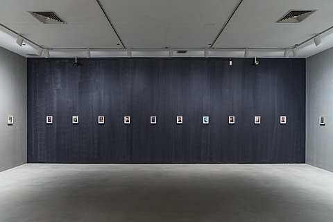 A dark wall with many small framed pictures of Chairman Mao hung in a straight line.