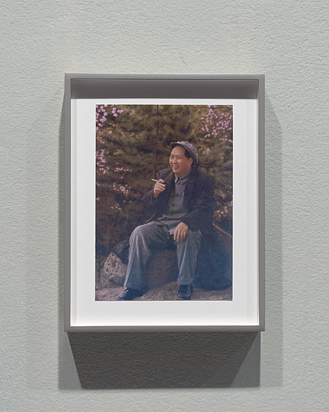 A framed picture of Chairman Mao playing smoking a cigarette.